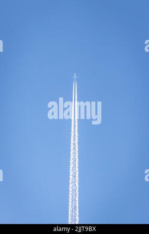 Plan vertical d'un avion quittant un sentier en volant dans le ciel bleu Banque D'Images