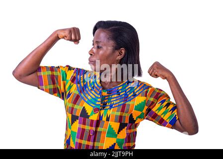 belle femme adulte vêtue de tissu de longe traditionnel, debout et regardant ses biceps. Banque D'Images