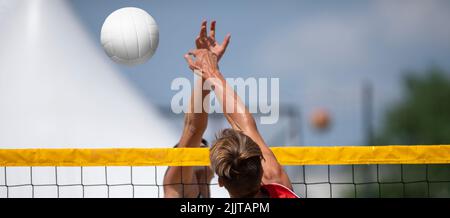 Homme d'athlétisme sautant pour faire un bloc mural au filet de Beach-volley. Affiche sur le thème du sport horizontal, cartes de vœux, en-têtes, site Web et application Banque D'Images