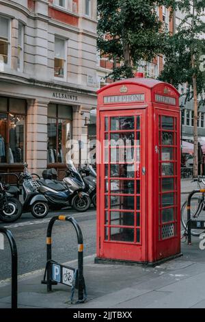 Un cliché vertical d'une cabine téléphonique rouge à Londres, au Royaume-Uni, dans la rue ensoleillée en plein air Banque D'Images