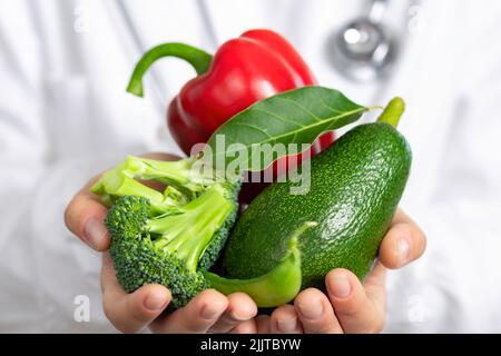 Alimentation saine le médecin nutritionniste tient l'avocat et les poivrons frais de brocoli dans ses mains Banque D'Images