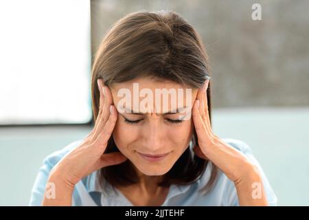 Portrait de la jeune femme caucasienne avec des maux de tête frottant ses temples Banque D'Images