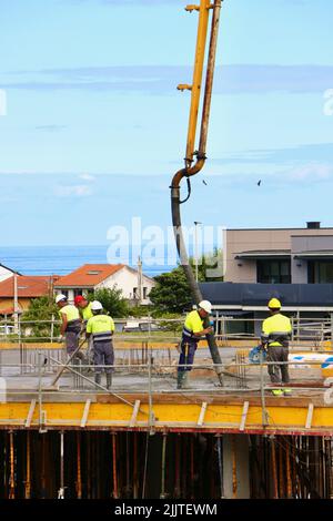 Les ouvriers de la construction peignent le béton récemment versé d'un bras de flèche pompé sur le nouveau plancher d'un bloc d'appartements Santander Cantabria Espagne Banque D'Images