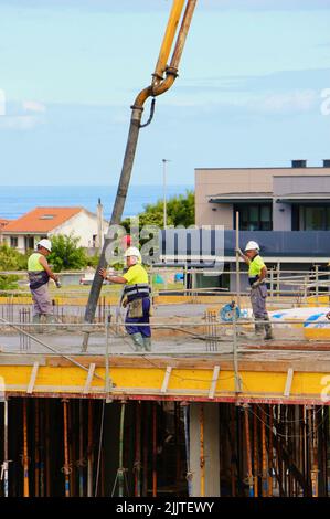 Les ouvriers de la construction peignent le béton récemment versé d'un bras de flèche pompé sur le nouveau plancher d'un bloc d'appartements Santander Cantabria Espagne Banque D'Images