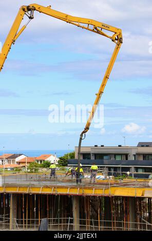 Les ouvriers de la construction peignent le béton récemment versé d'un bras de flèche pompé sur le nouveau plancher d'un bloc d'appartements Santander Cantabria Espagne Banque D'Images