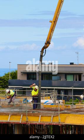 Les ouvriers de la construction peignent le béton récemment versé d'un bras de flèche pompé sur le nouveau plancher d'un bloc d'appartements Santander Cantabria Espagne Banque D'Images