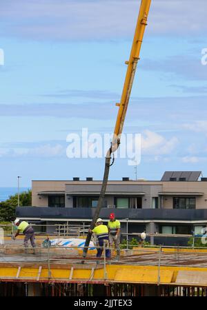 Les ouvriers de la construction peignent le béton récemment versé d'un bras de flèche pompé sur le nouveau plancher d'un bloc d'appartements Santander Cantabria Espagne Banque D'Images