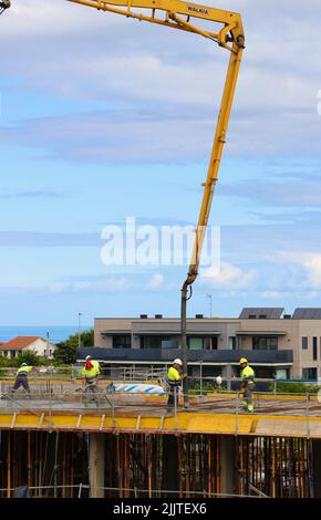 Les ouvriers de la construction peignent le béton récemment versé d'un bras de flèche pompé sur le nouveau plancher d'un bloc d'appartements Santander Cantabria Espagne Banque D'Images