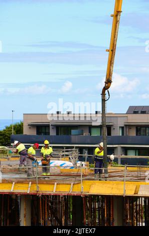 Les ouvriers de la construction peignent le béton récemment versé d'un bras de flèche pompé sur le nouveau plancher d'un bloc d'appartements Santander Cantabria Espagne Banque D'Images