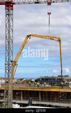 Les ouvriers de la construction peignent le béton récemment versé d'un bras de flèche pompé sur le nouveau plancher d'un bloc d'appartements Santander Cantabria Espagne Banque D'Images