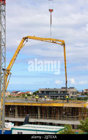 Les ouvriers de la construction peignent le béton récemment versé d'un bras de flèche pompé sur le nouveau plancher d'un bloc d'appartements Santander Cantabria Espagne Banque D'Images