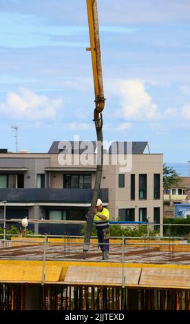 Les ouvriers de la construction peignent le béton récemment versé d'un bras de flèche pompé sur le nouveau plancher d'un bloc d'appartements Santander Cantabria Espagne Banque D'Images