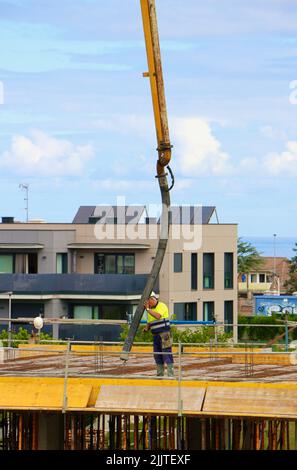 Les ouvriers de la construction peignent le béton récemment versé d'un bras de flèche pompé sur le nouveau plancher d'un bloc d'appartements Santander Cantabria Espagne Banque D'Images