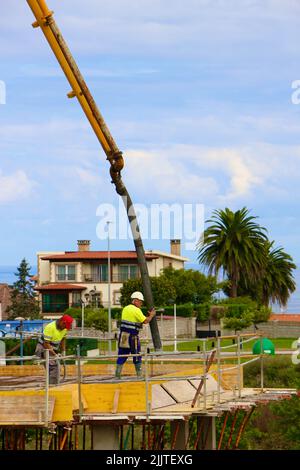 Les ouvriers de la construction peignent le béton récemment versé d'un bras de flèche pompé sur le nouveau plancher d'un bloc d'appartements Santander Cantabria Espagne Banque D'Images