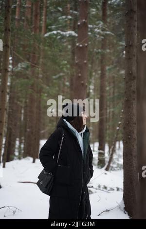 Une photo verticale d'une jeune femme du Caucase dans les bois enneigés Banque D'Images