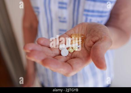 Dans les mains d'une femme âgée, une poignée de pilules et de vitamines diverses. Banque D'Images