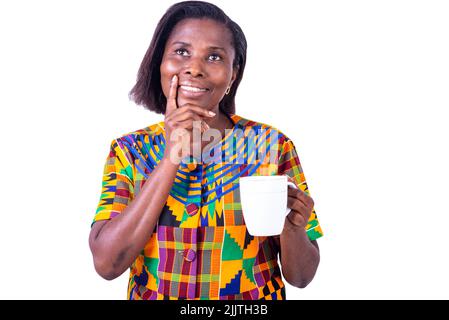 belle femme mûre pensive debout avec une tasse de café à la main tout en souriant. Banque D'Images