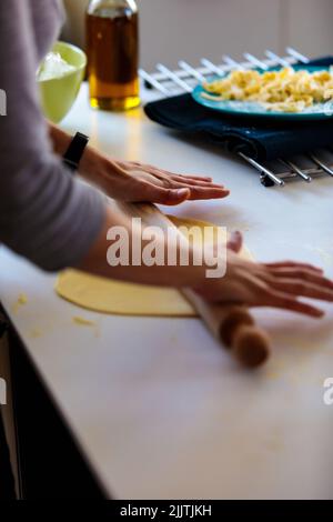Un cliché vertical d'une personne qui roule une pâte avec un rouleau dans la cuisine Banque D'Images