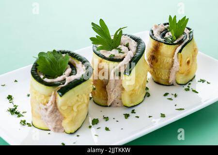 Rouleaux de courgettes grillées au thon et au fromage à la crème sur fond vert Banque D'Images