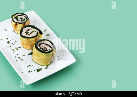 Rouleaux de courgettes grillées au thon et au fromage à la crème sur fond vert Banque D'Images