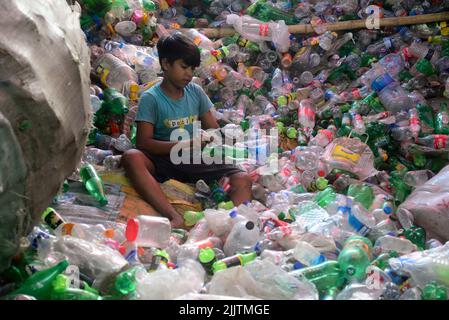 Les enfants qui travaillent passent par des bouteilles en polyéthylène téréphtalate (PET) dans une usine de recyclage à Dhaka, au Bangladesh, en 27 juillet 2022. Recyclage du plastique Banque D'Images