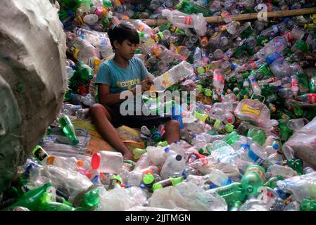 Les enfants qui travaillent passent par des bouteilles en polyéthylène téréphtalate (PET) dans une usine de recyclage à Dhaka, au Bangladesh, en 27 juillet 2022. Recyclage du plastique Banque D'Images