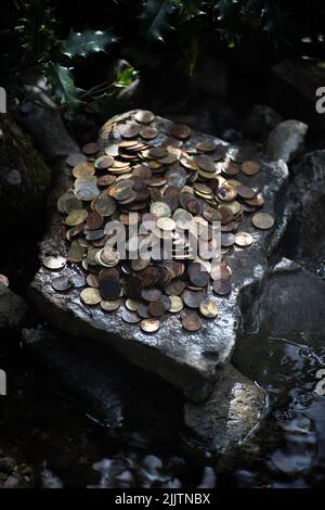 Un gros plan d'une pile de vieilles pièces de monnaie sur une pierre dans une forêt Banque D'Images