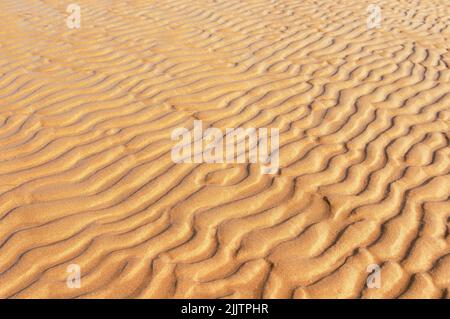 Vent sur la plage. Fond naturel de sable dans le motif ondulé vague Banque D'Images