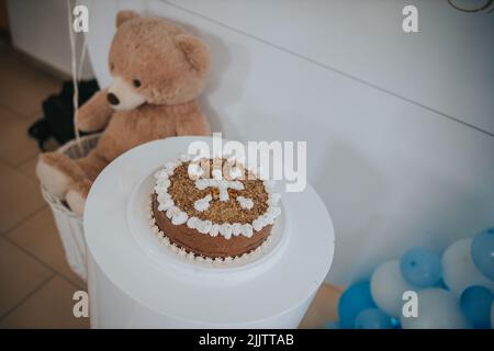 Gros plan d'un gâteau d'anniversaire sur une table blanche avec un ours en peluche à côté Banque D'Images