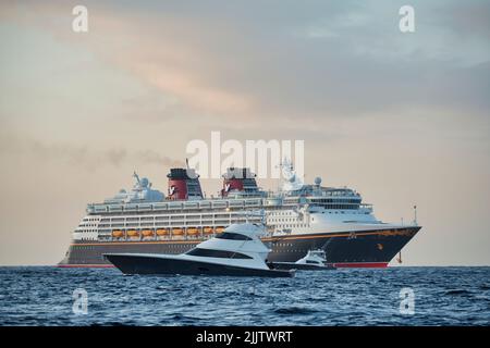 Un grand bateau de croisière et un petit bateau de pêche flottant sur l'eau Banque D'Images