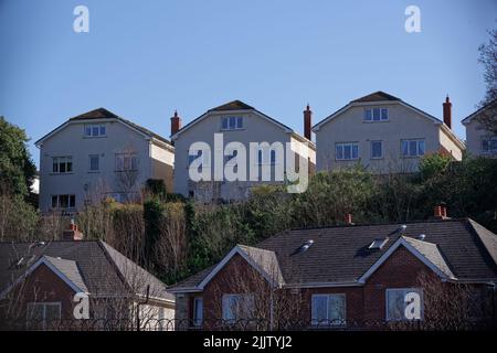 Rangée de maisons individuelles identiques construites sur la colline surplombant un quartier résidentiel. Banque D'Images