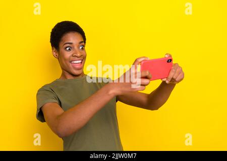 Portrait de drôle de personne folle tenir téléphone jouer jeux vidéo isolés sur fond jaune de couleur Banque D'Images
