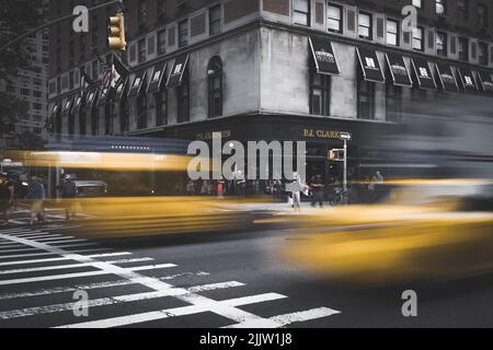 Une photo en niveaux de gris de taxis jaunes rapides et flous sur une route très fréquentée à New York Banque D'Images