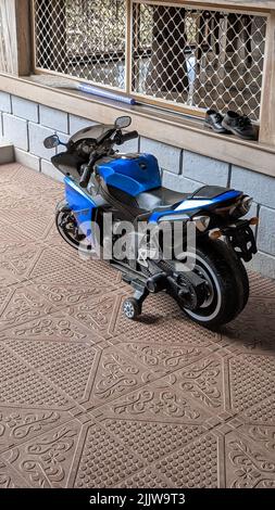 une moto bleue pour les enfants avec des roues d'entraînement garées dans la rue Banque D'Images