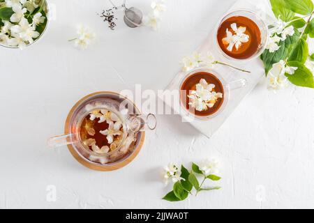 vue de dessus d'un fond blanc texturé avec une théière et deux tasses en verre avec thé au jasmin parfumé. boisson apaisante, calories minimales Banque D'Images