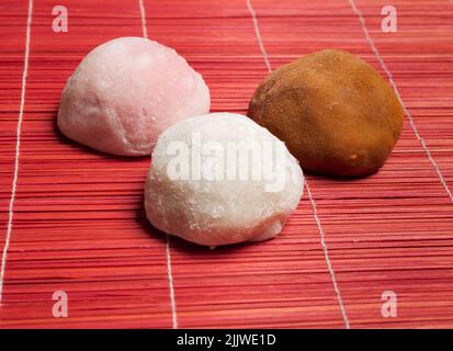 L'artisan mochis est décoré de trois saveurs sur une nappe en bois rouge avec vue de face Banque D'Images