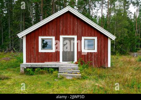 Skuleskogen, Suède - 08.22.2021: Cabine en bois rouge dans la forêt du parc national de Skuleskogen en Suède, par une journée nuageux. Panneaux en bois à l'avant. Banque D'Images