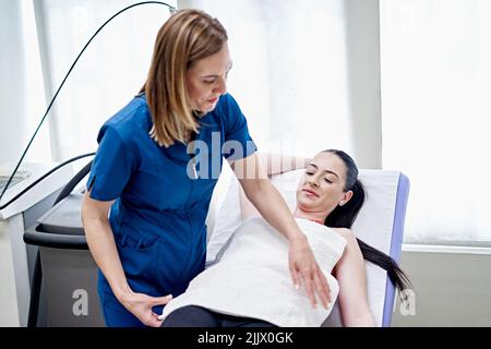 Une esthéticienne couvrant la femme avec une serviette blanche propre avant l'épilation en studio esthétique Banque D'Images