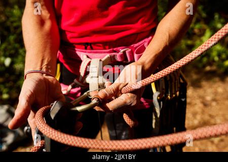 Court non reconnaissable de la corde de nouage de femme senior active sur le harnais lors de la préparation à l'escalade Banque D'Images