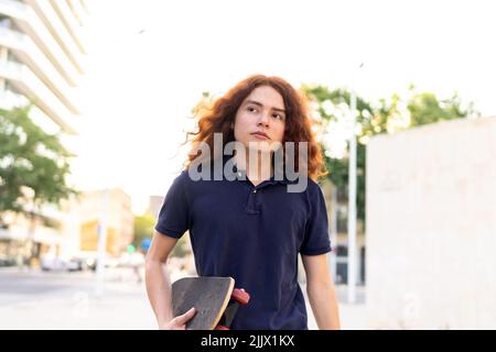 Portrait d'une jeune femme avec planche à roulettes debout en ville Banque D'Images
