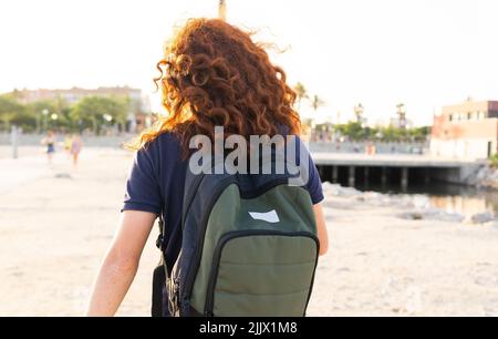 Vue arrière de la jeune femme avec tête rouge et sac à dos contre la ville Banque D'Images
