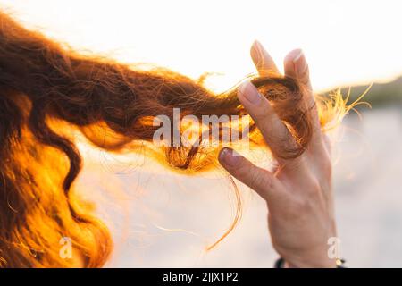 Image rognée de la main jouant avec des cheveux bouclés Banque D'Images