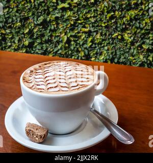 Gros plan de café blanc avec mousse latte décorée sur la table en bois dans le jardin du Brésil Banque D'Images