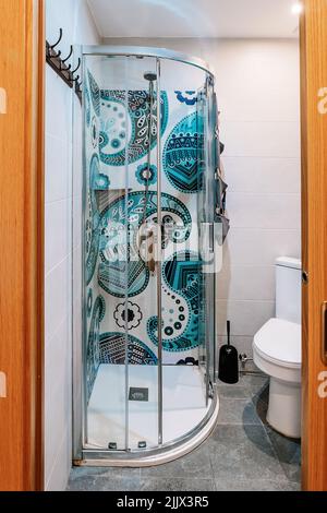 Cuvette de toilette en céramique blanche près de cabine de douche en verre et lavabo dans la petite salle de bains Banque D'Images