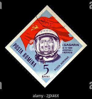 Yuri Gagarin, astronaute soviétique, premier homme dans l'espace, drapeau soviétique rouge, vers 1964. Timbre postal annulé imprimé en Roumanie isolé sur noir Banque D'Images