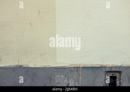 Mur en plâtre d'un ancien bâtiment peint dans différentes teintes de couleur crème sur la rue de la ville en journée Banque D'Images