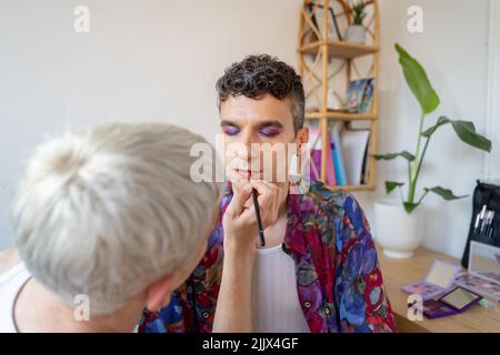 Jeune homme androgyne se maquiller fait par son petit ami à la table de dressing Banque D'Images