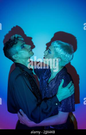 Portrait d'un couple gay portant un maquillage et enveloppant dans un studio lumineux Banque D'Images