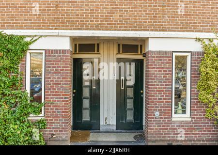 Façade de bâtiment résidentiel en brique avec fenêtre et porte d'entrée fermée située sur la rue avec des plantes vertes en ville Banque D'Images