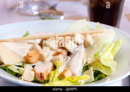 Une salade César classique, joliment présentée, servie à une table de restaurant. La salade est recouverte d'une sauce crémeuse et de croûtons Banque D'Images